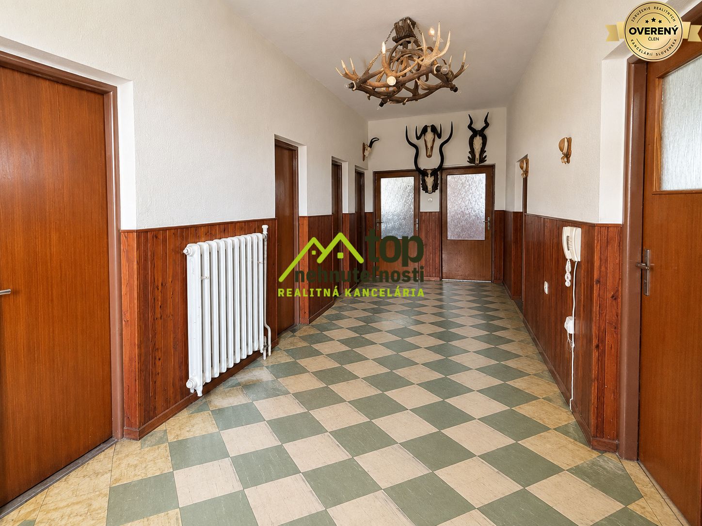 Chodba s dlaždicovou podlahou a dreveným obložením, dekorácie z parohov. Rodinný dom.