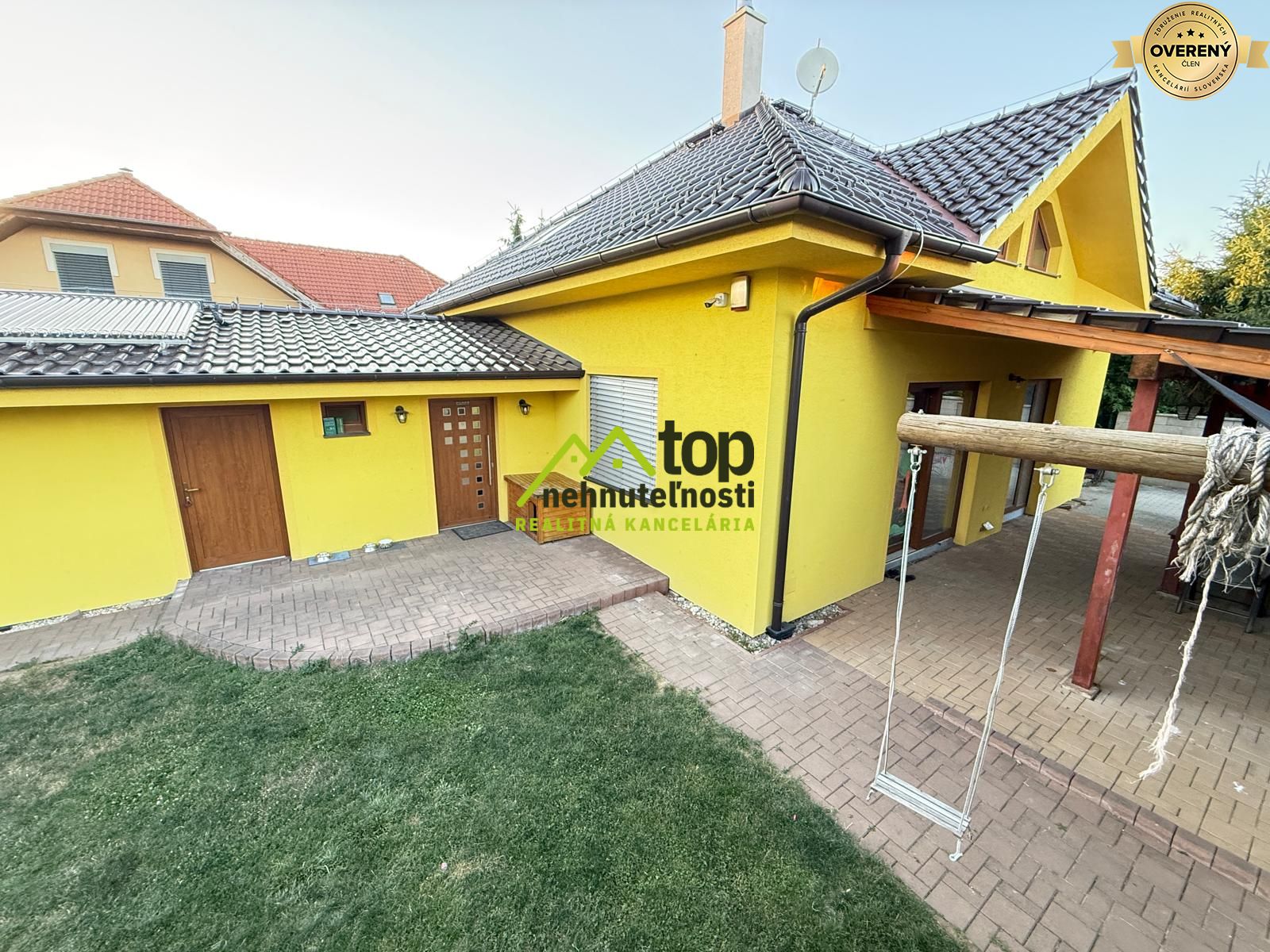 Žltý rodinný dom v Topoľčanoch so šindľovou strechou a hojdačkou na dvore.