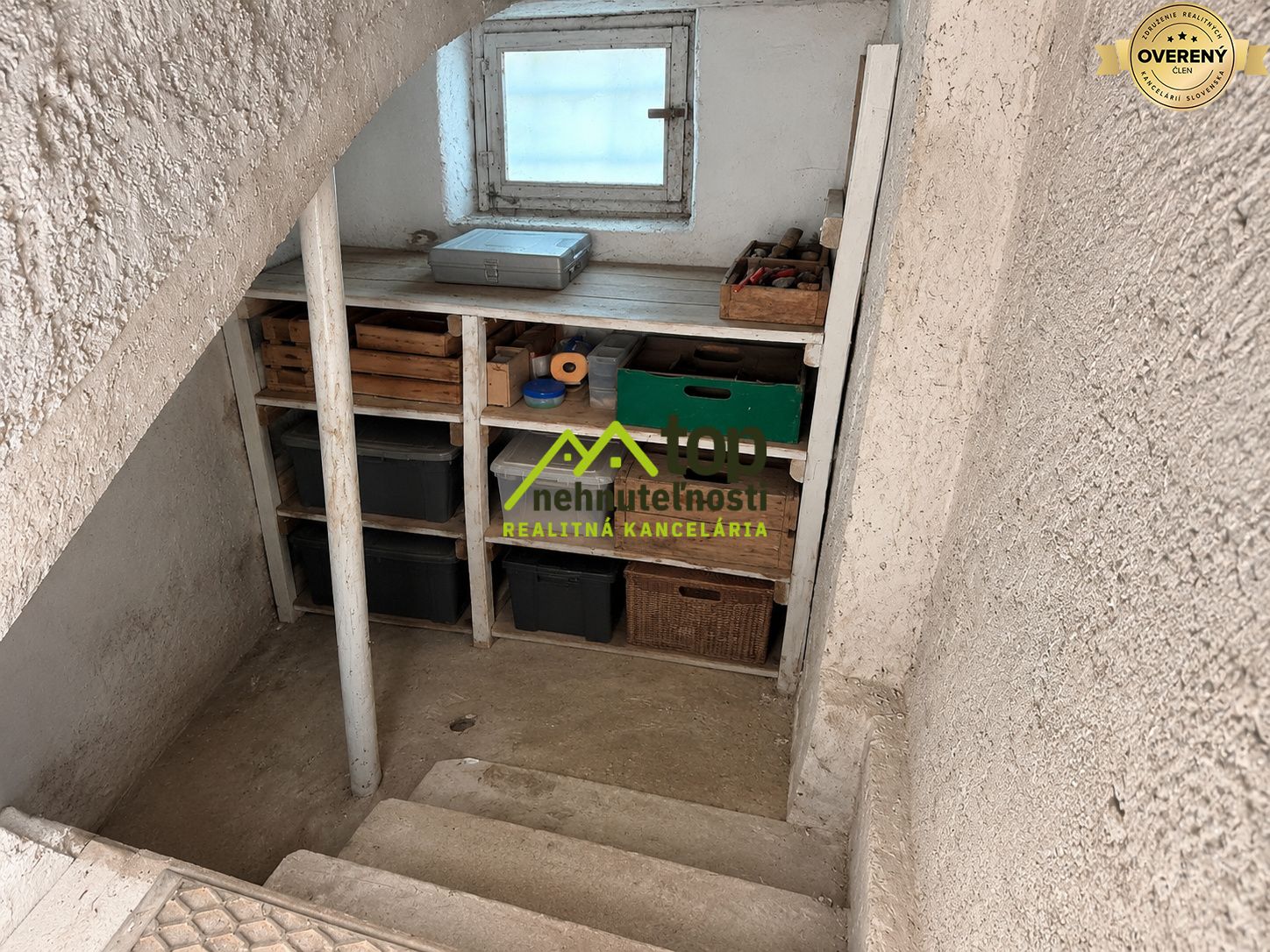 Skladovací priestor so schodiskom v rodinnom dome, poličky s úložnými boxmi.