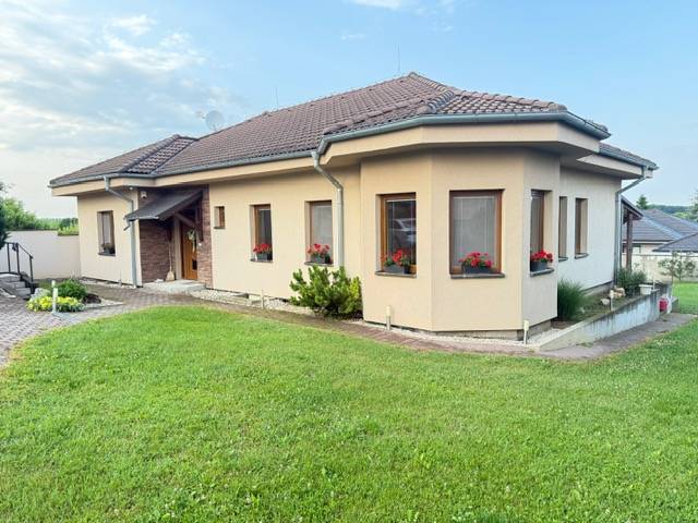 Rodinný dom vo Veľkom Záluží obklopený trávnikom a kvetmi na oknách.