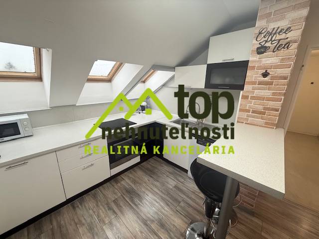 Kuchyňa v 1-izbovom byte s podlahou s dreveným dekorom a strešnými oknami.