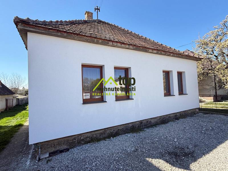 Rodinný dom vo Veľkých Ripňanoch, biely exteriér, šikmá strecha, štrk okolo stavby.