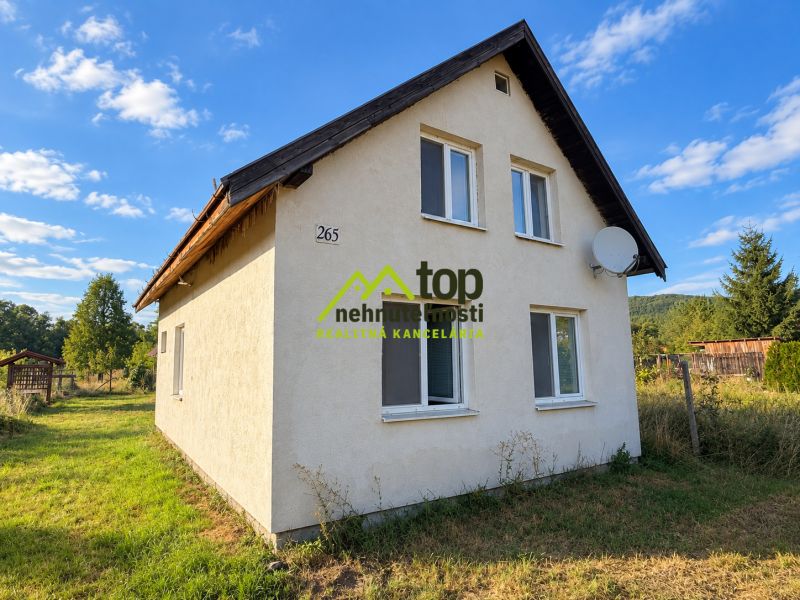 Rodinný dom vo Veľkom Klíži obklopený zelenými záhradami a modrou oblohou.